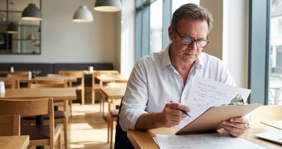 UK restaurant owner reviewing financial strategies on a clipboard
