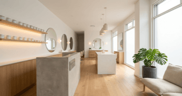 Modern minimalist beauty salon with light oak accents, concrete desk, and LED strip lighting