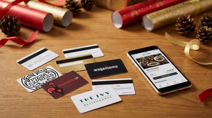 A selection of restaurant gift cards displayed alongside British pound coins on a restaurant counter
