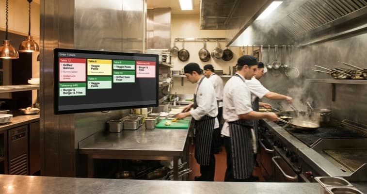 Kitchen display system screen mounted in a UK restaurant kitchen showing live orders