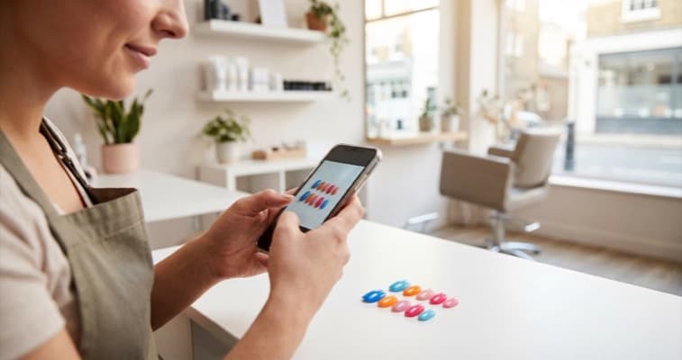 Salon marketing ideas for social media showing a beauty therapist photographing nail art for Instagram